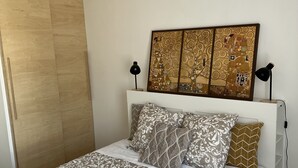 A bedroom with a bed, a hanging light fixture, a wall art piece, and a bedside table. - A 20 Mètres des Remparts Appartement Avec Parking (Avignon)