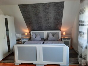 A bedroom with a bed, two bedside tables, a wardrobe, and a textured wall.