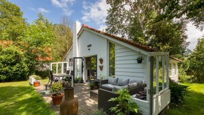 Una cabaña acogedora con un patio, mobiliario exterior y plantas en macetas.