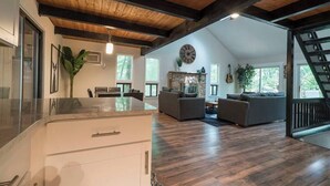 A spacious living area with a wooden ceiling, a stone fireplace, and a large clock on the wall.