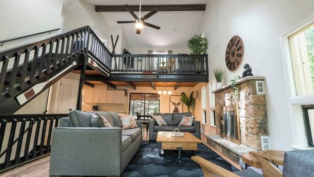 A spacious living area with a staircase, a fireplace, and a clock on the wall.