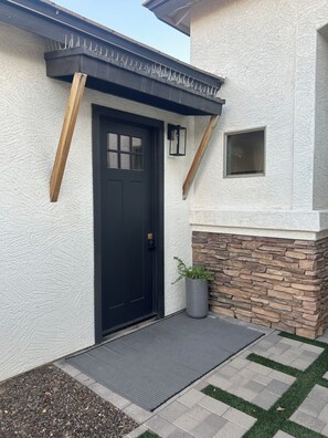 A house with a black door, a stone accent wall, and a potted plant.