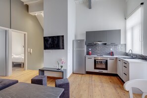 A modern kitchen with grey cabinets, a stainless steel refrigerator, and a tiled backsplash.