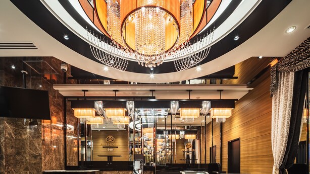 Een weelderige hotellobby met een statig kroonluchter, marmeren vloeren en een receptiebalie.