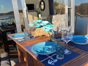 Ein Holztisch mit blauem Glas und Geschirr, eine dekorative Fischskulptur und ein Logo auf der Tischunterlage.