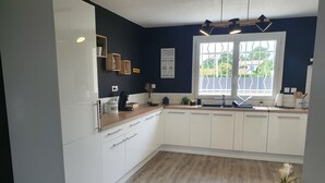 Een moderne keuken met witte kastjes, een houten aanrecht en een raam met uitzicht op groen.