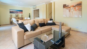 A spacious living room with a beige sectional sofa, a glass coffee table, and a painting on the wall. - Outstanding one bedroom apart with heated private pool in Vale do Lobo (Almancil)