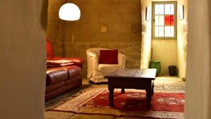 Un cuarto acogedor con un arco de piedra, un sofá de cuero rojo, un sillón blanco, una mesa de madera y una lámpara de pie.