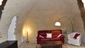 Una habitación acogedora con un sofá de cuero rojo, un sillón blanco, una mesa de centro de madera y una lámpara de pie.