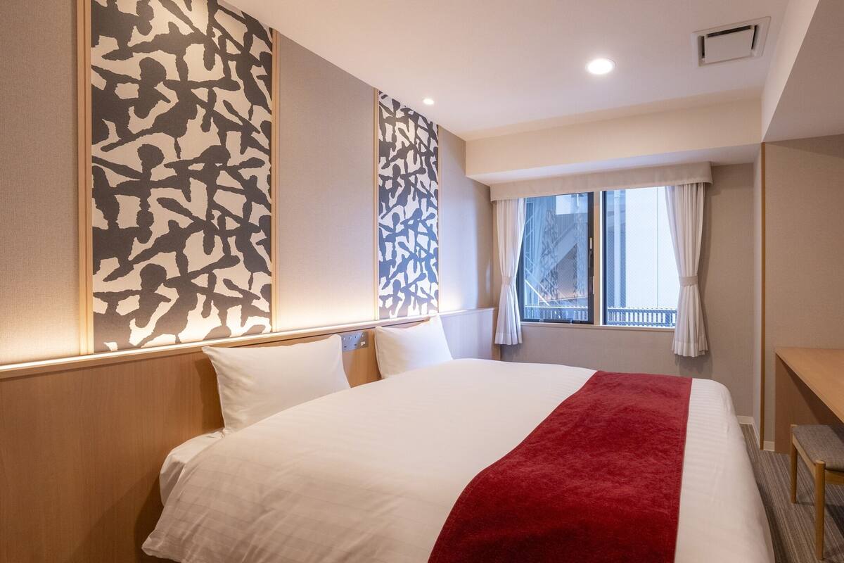 Une chambre d’hôtel avec un grand lit, un bureau, une télévision et une fenêtre avec des rideaux.