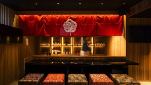 Een bar met een rood gordijn, houten lambrisering en een barman.