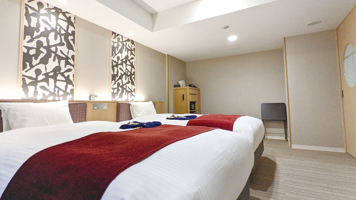 Une chambre d’hôtel avec deux lits, un bureau, une chaise, une armoire et un miroir.