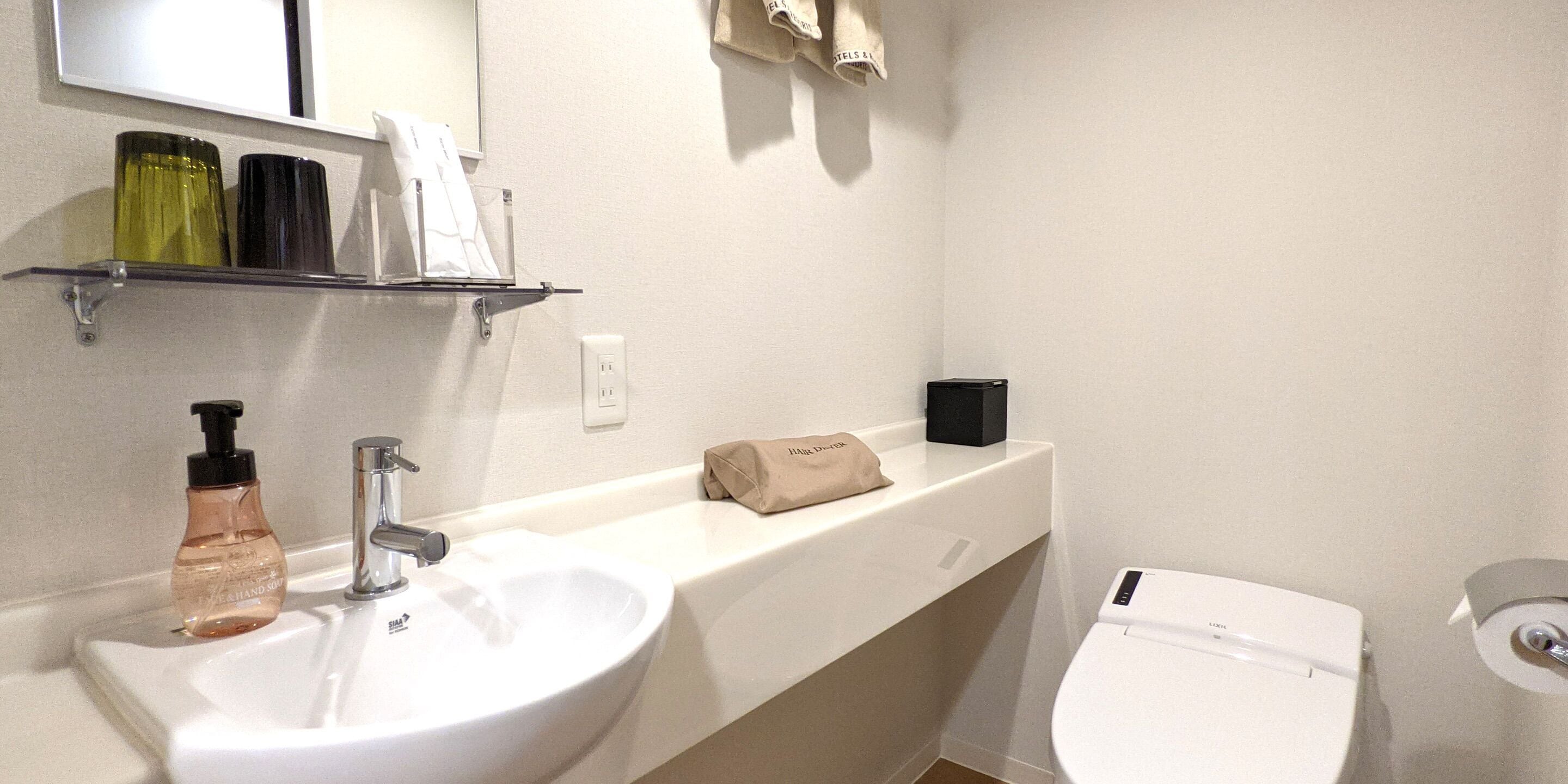 A bathroom with a white sink, a mirror, a towel rack, and a toilet.