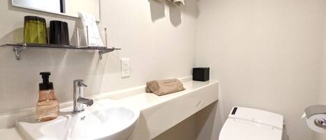 A bathroom with a white sink, a mirror, a towel rack, and a toilet.