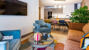 Una sala moderna con un sofá, sillones, una mesa de centro y un comedor al fondo.