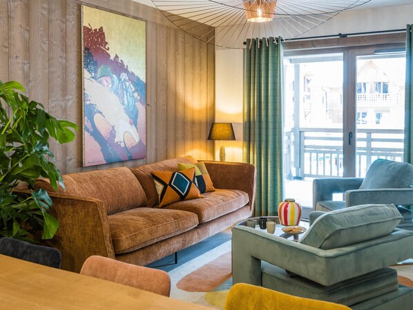 A living room with a brown sofa, a grey armchair, and a coffee table with a striped vase. - Luxury Apartment in Village Center with Modern Amenities (Les Gets)