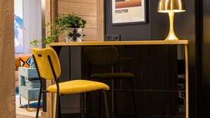 Un área de bar moderna con una mesa de madera, dos sillas, una planta en maceta y una obra de arte enmarcada en la pared.