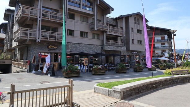 Un hotel de varios pisos con terraza al aire libre y macetas con flores.