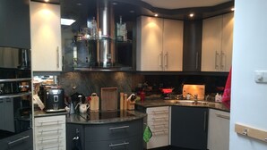 A modern kitchen with a central island, stainless steel appliances, and a variety of utensils and appliances. - Grote Familiewoning Heel Dicht bij het Strand (Noordwijk Zh)