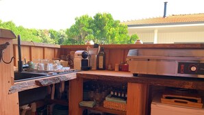 A compact outdoor kitchen with a wooden counter, a sink, and various cooking appliances.
