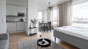 Eine moderne Wohnung mit einer Küchenzeile, einem Essbereich und einem Schlafzimmer mit großem Fenster.