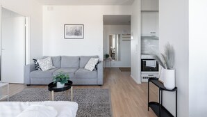 Ein modernes Wohnzimmer mit einem grauen Sofa, einem kleinen Beistelltisch mit einer Pflanze und einer schwarzen Ablagetisch mit einer Vase.