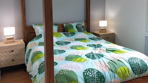 A four-poster bed with a floral bedspread, two bedside tables with lamps, and a woven hanging light fixture. - Maison de Vacance Tout Confort Avec Piscine (saint benoit du sault)