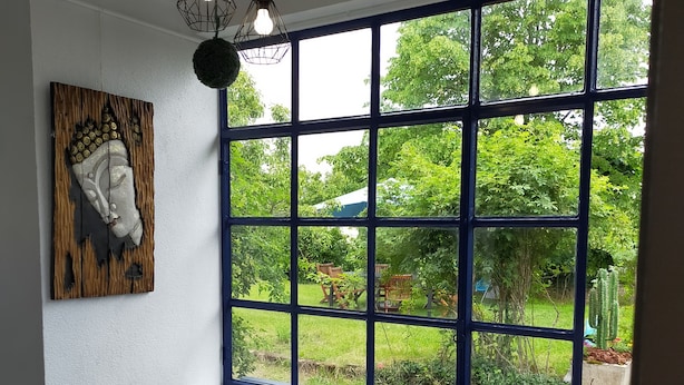 A room with a large window, a chair, a small table, and a mosaic floor. - Maison de Vacance Tout Confort Avec Piscine (saint benoit du sault)