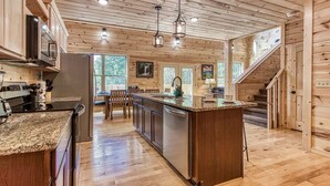 A spacious kitchen with wooden cabinetry, granite countertops, stainless steel appliances, and a central island. - Splish-N-Splash · Private Indoor Pool, Hot Tub, $560 FREE tickets each paid day (Sevierville)
