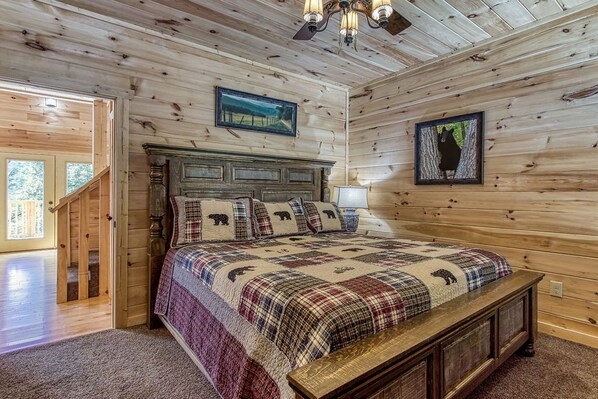 A wooden-paneled bedroom with a bed, a wooden bench, a chandelier, and framed pictures on the walls. - Splish-N-Splash · Private Indoor Pool, Hot Tub, $560 FREE tickets each paid day (Sevierville)