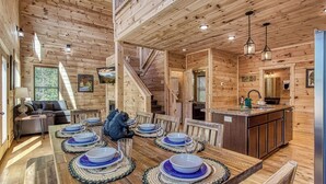 A wooden cabin interior with a dining area, kitchen, and staircase. - Splish-N-Splash · Private Indoor Pool, Hot Tub, $560 FREE tickets each paid day (Sevierville)