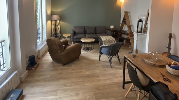 A spacious living area with a sofa, chairs, a dining table, and a guitar.