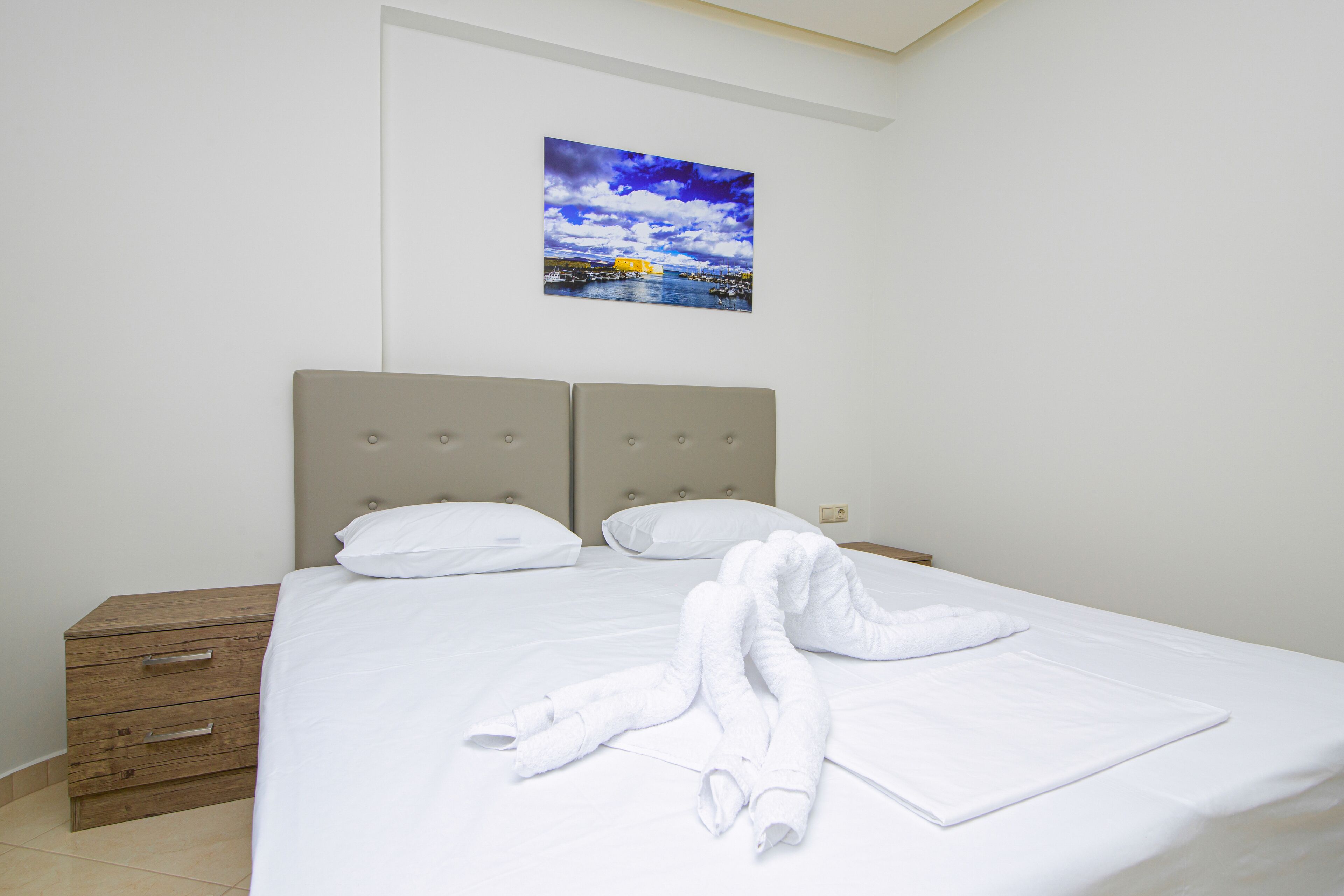 A neatly made bed with white linens and a towel laid out on the bed.