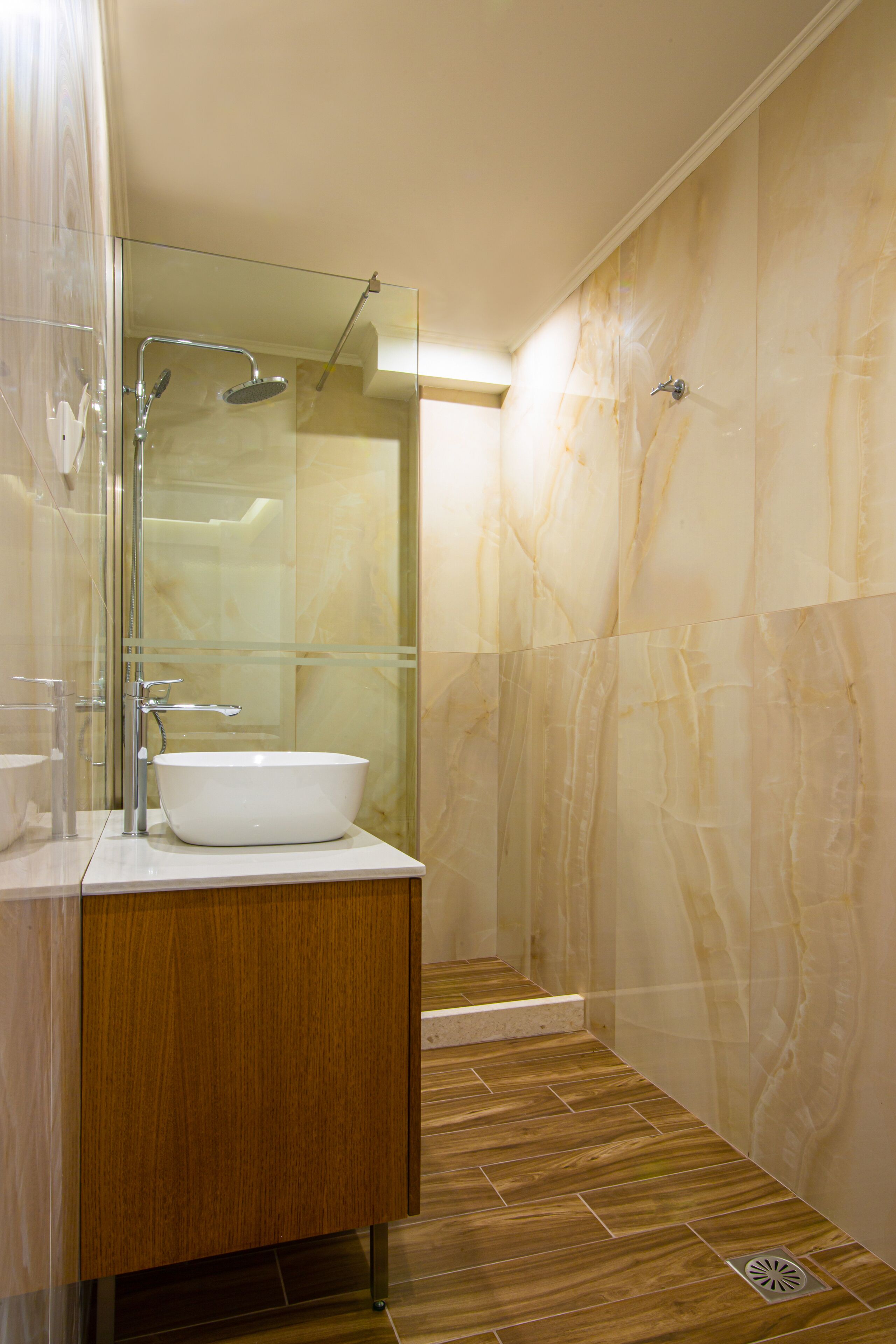 A modern bathroom with a glass-enclosed shower, a white sink, and wooden cabinetry.