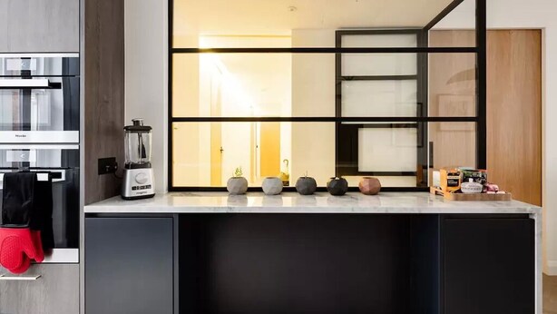 Una cocina moderna con una licuadora integrada, una cafetera y una variedad de ollas y sartenes sobre la encimera.
