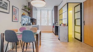 Una cocina moderna con comedor, que cuenta con un amplio ventanal, una lámpara colgante y una puerta de madera.