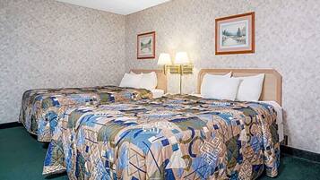 A hotel room with a large bed, two bedside lamps, and two framed pictures on the wall.