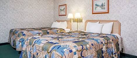 A hotel room with a large bed, two bedside lamps, and two framed pictures on the wall.