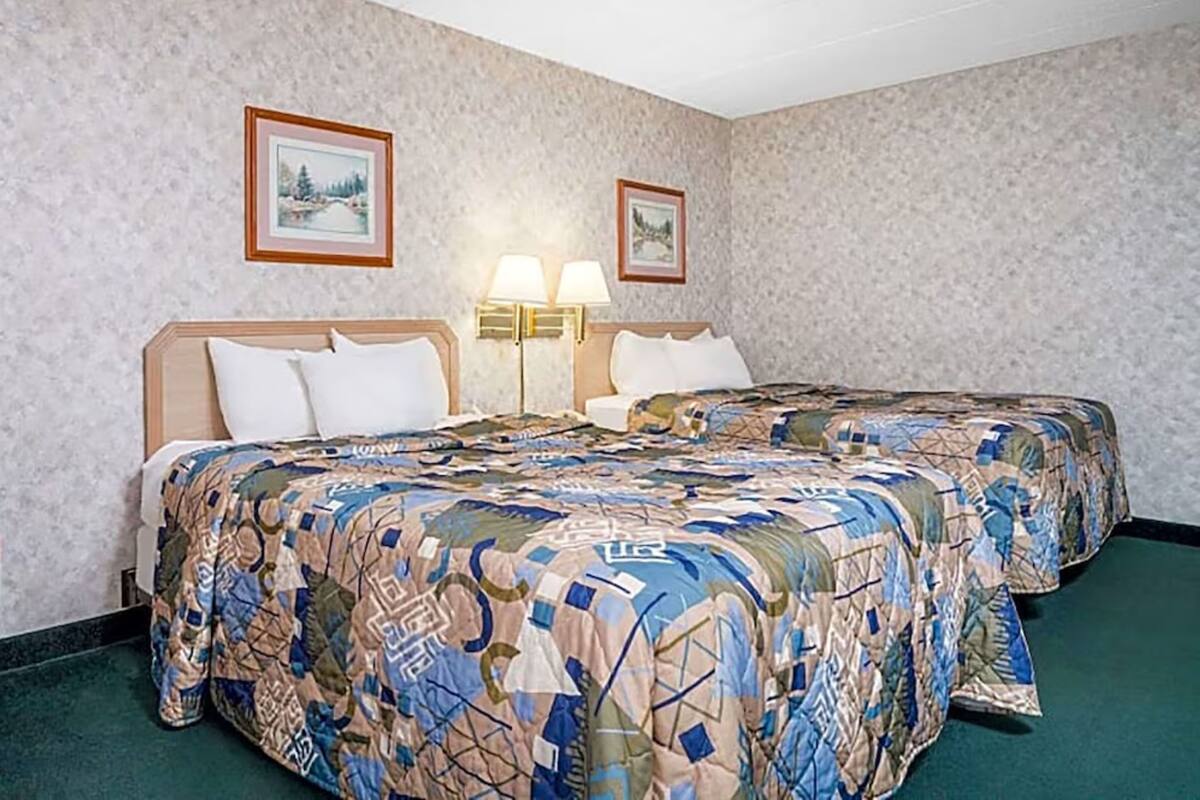 Ein Hotelzimmer mit zwei Betten, einem grünen Teppich und zwei Wandlampen.