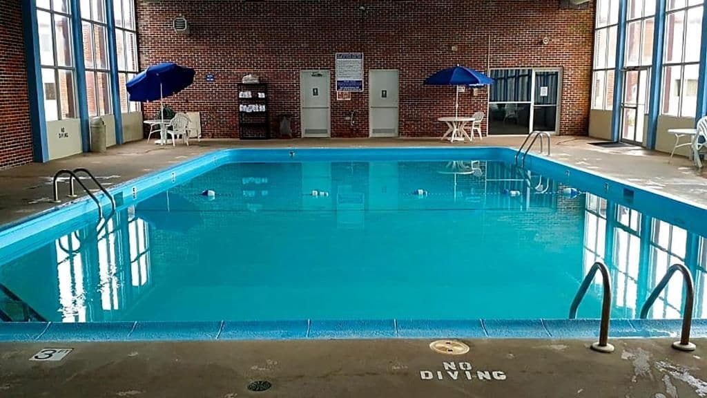 An indoor swimming pool with clear water, surrounded by brick walls and large windows.