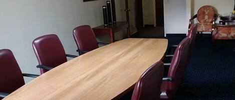 A conference room with a long wooden table and red chairs.