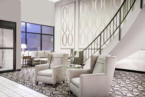 Un salon moderne avec un sol à motifs, un escalier et une grande fenêtre.