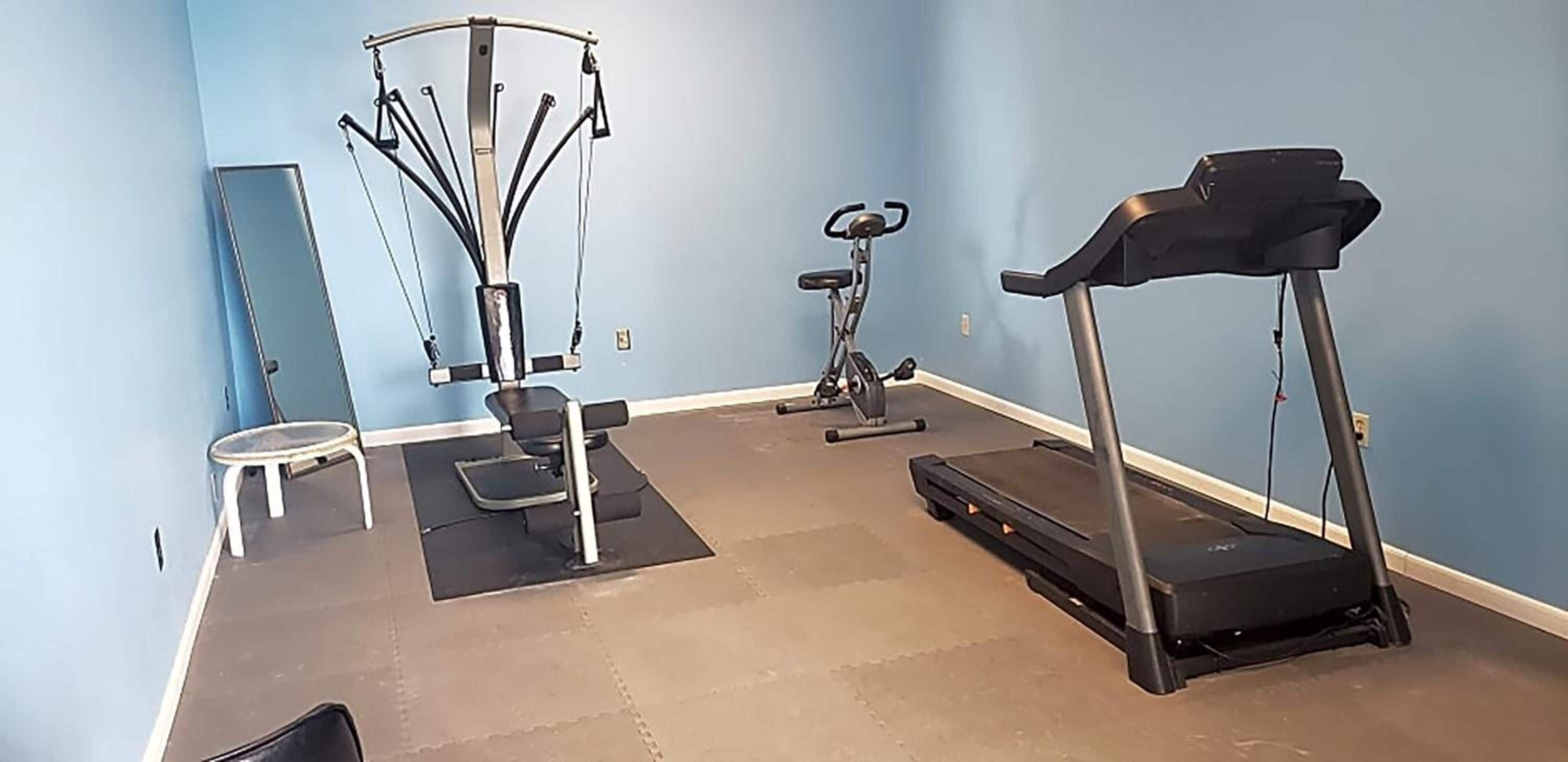 A home gym with a treadmill, elliptical, and stationary bike.