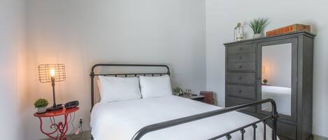 A bedroom with a bed, a nightstand, a lamp, a dresser, and a ceiling fan.
