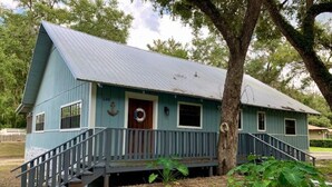 A blue house with a porch, a wooden door, and a small staircase leading up to it. - Rustic newly remodeled River House on working fish house property . Gulf access (Inglis)