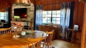 A wooden dining area with a large table, chairs, and a fireplace. - Rustic newly remodeled River House on working fish house property . Gulf access (Inglis)
