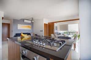 Une cuisine moderne dotée d’un îlot central, d’un four encastré et d’un ventilateur de plafond.