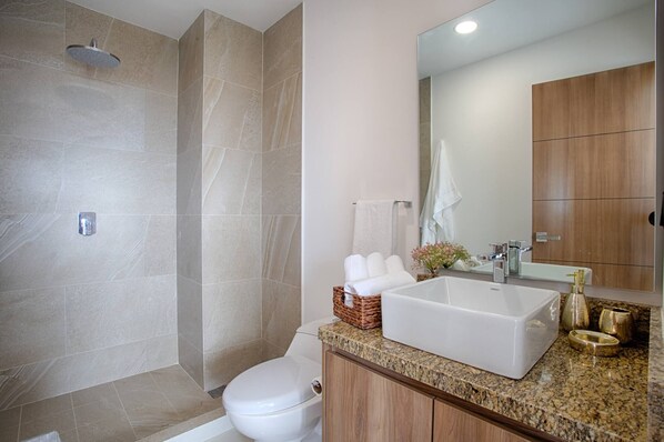 A modern bathroom with a shower, toilet, sink, and vanity.
