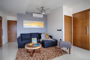Una sala moderna con sofá, reposapiés, mesa de centro y ventilador de techo.