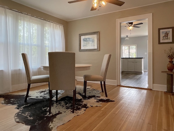 A dining area with a wooden floor, a cowhide rug, and a ceiling fan. - The Buckaroo- walk to historic downtown Cody, dog friendly! (Cody)